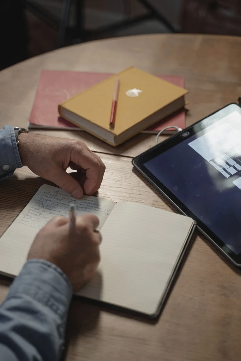 Persona tomando notas junto a una tablet, evaluación de TDAH en adultos en Valladolid